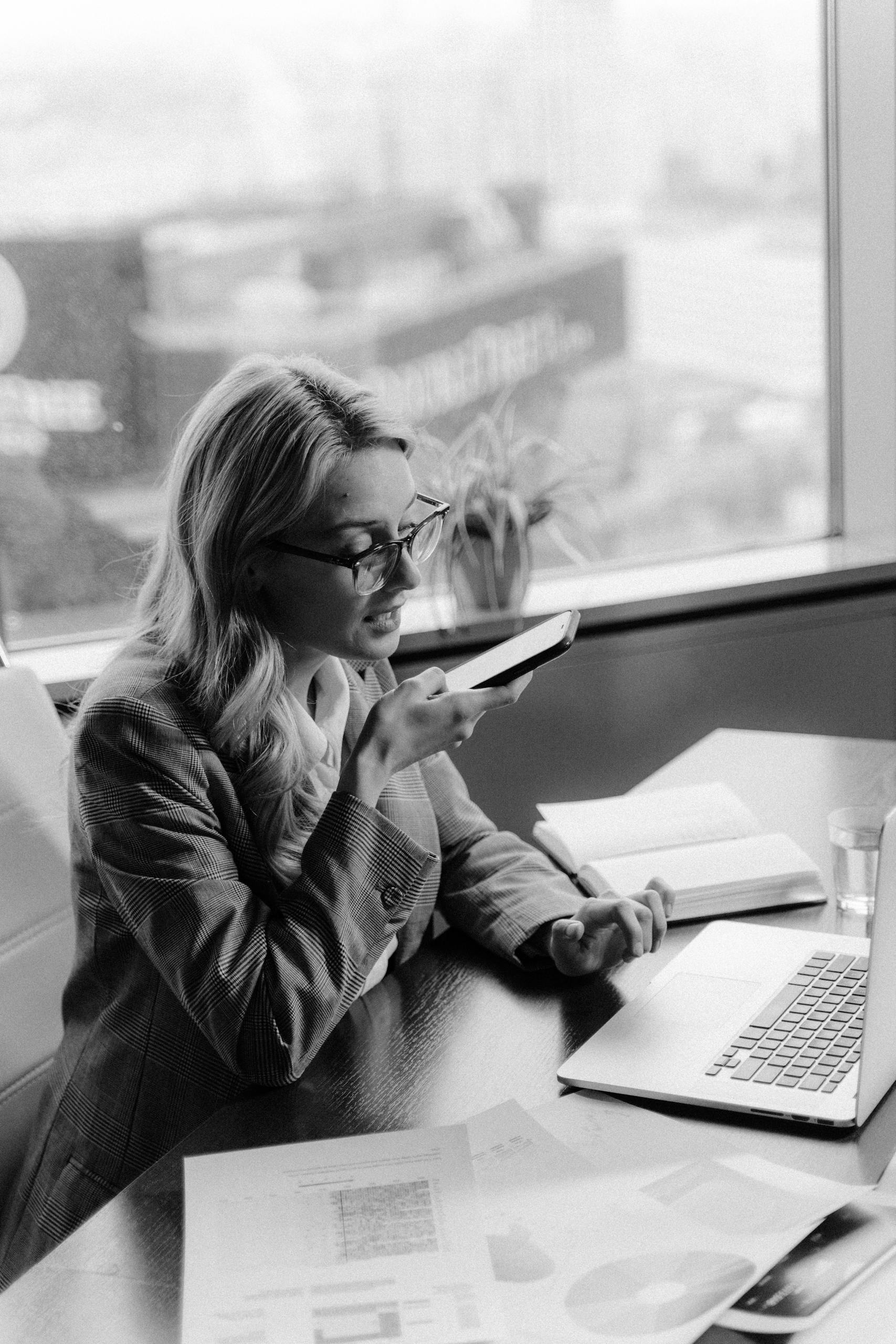 Black and white photo of a woman using voice commands in an office setting.